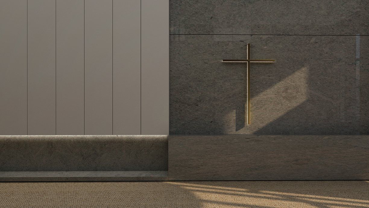 A brass cross on a dark stone wall beside pale timber panels.