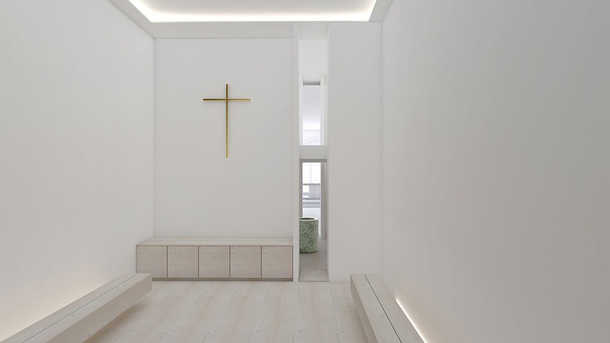 A white room with a brass cross on the end wall and low benches along the sides.