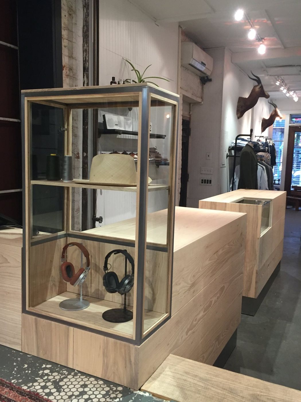 A glass and metal display case with hats and headphones on a timber counter.