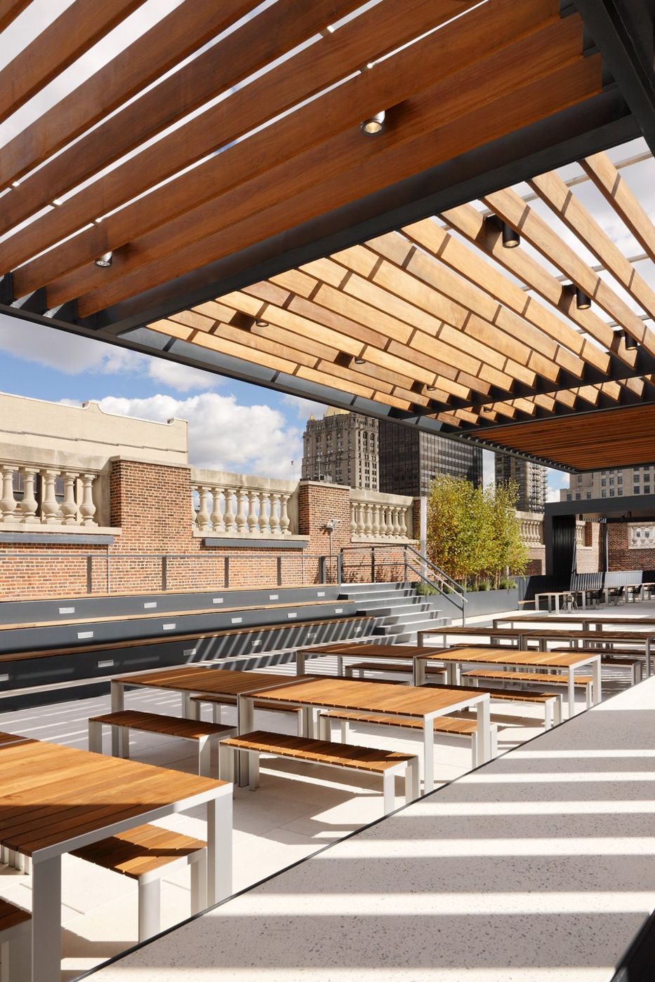 Looking out under the timber louvres over tables towards steps and a parapet.
