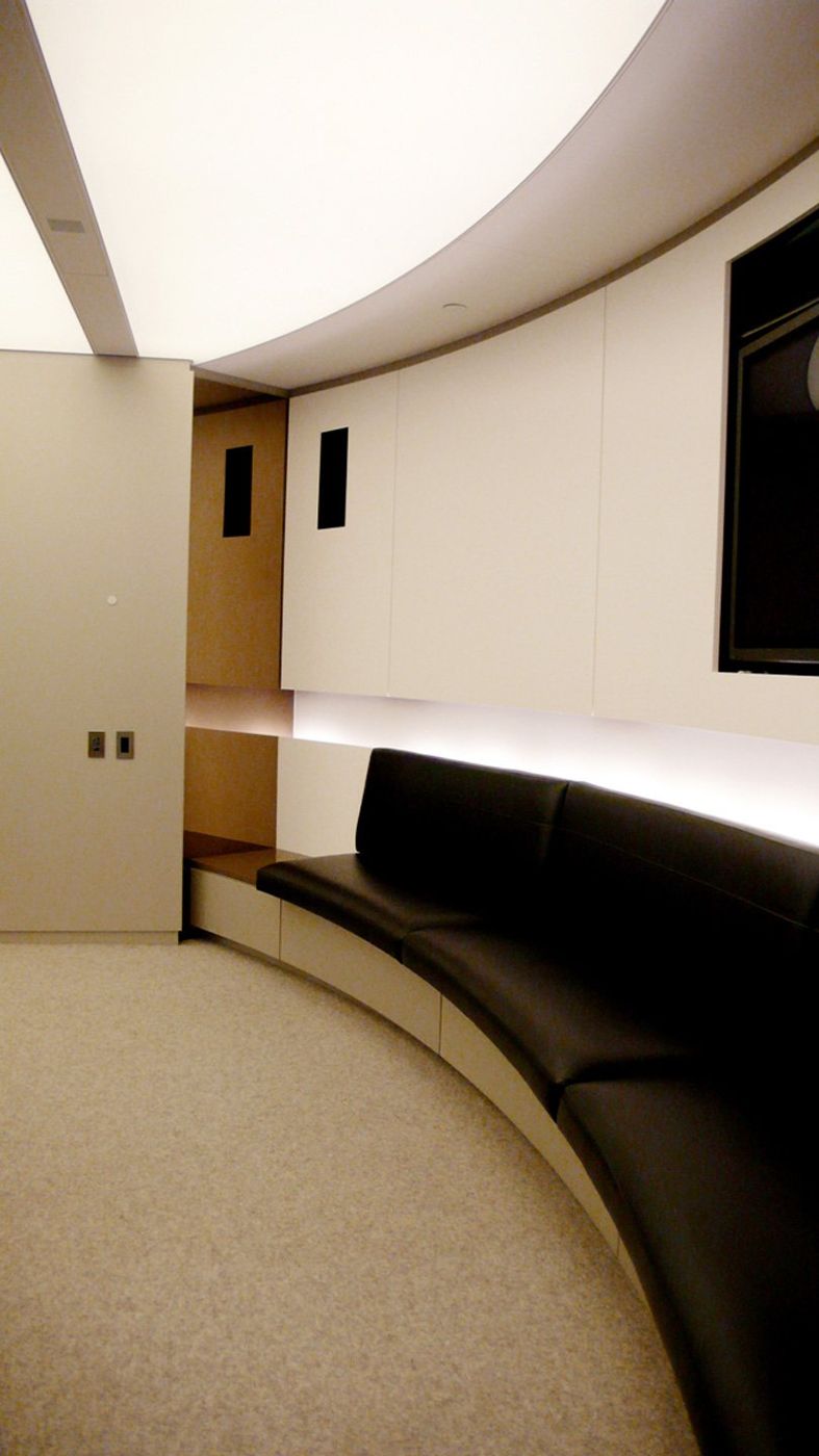 A dark leather banquette following a curved wall under a lit cove.