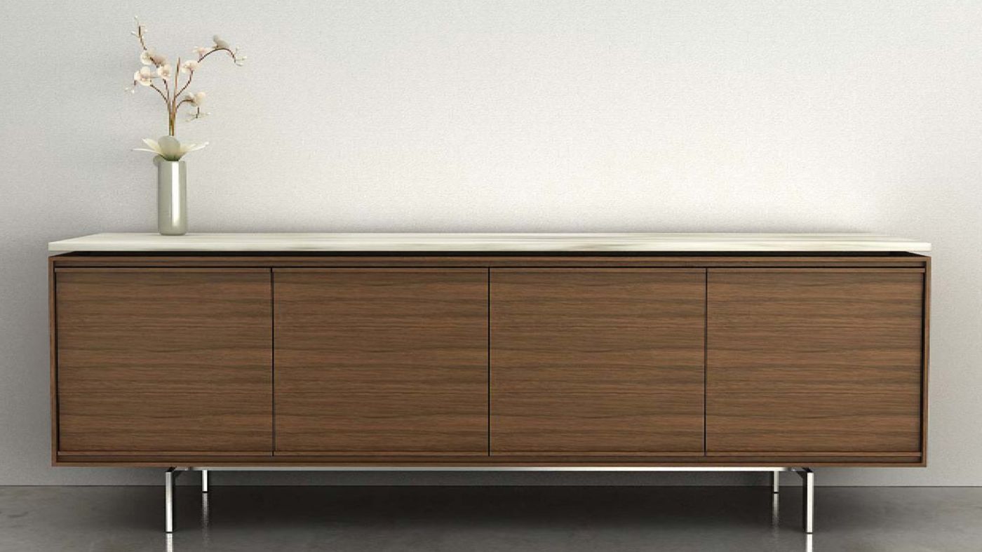 A low timber credenza on slim steel legs against a pale wall.