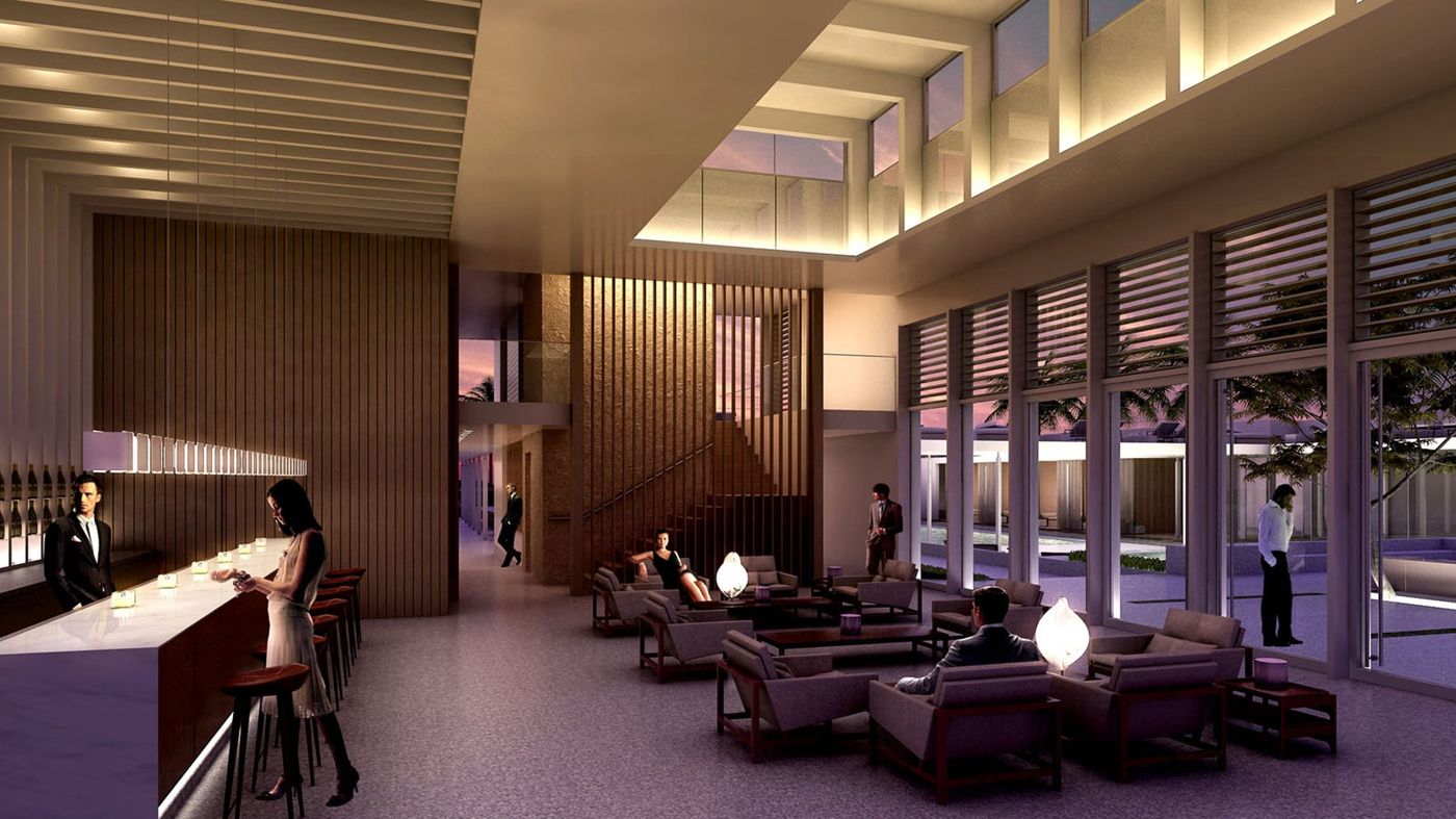 An evening view of a tall bar room with a lit counter, timber screens and lounge seating.