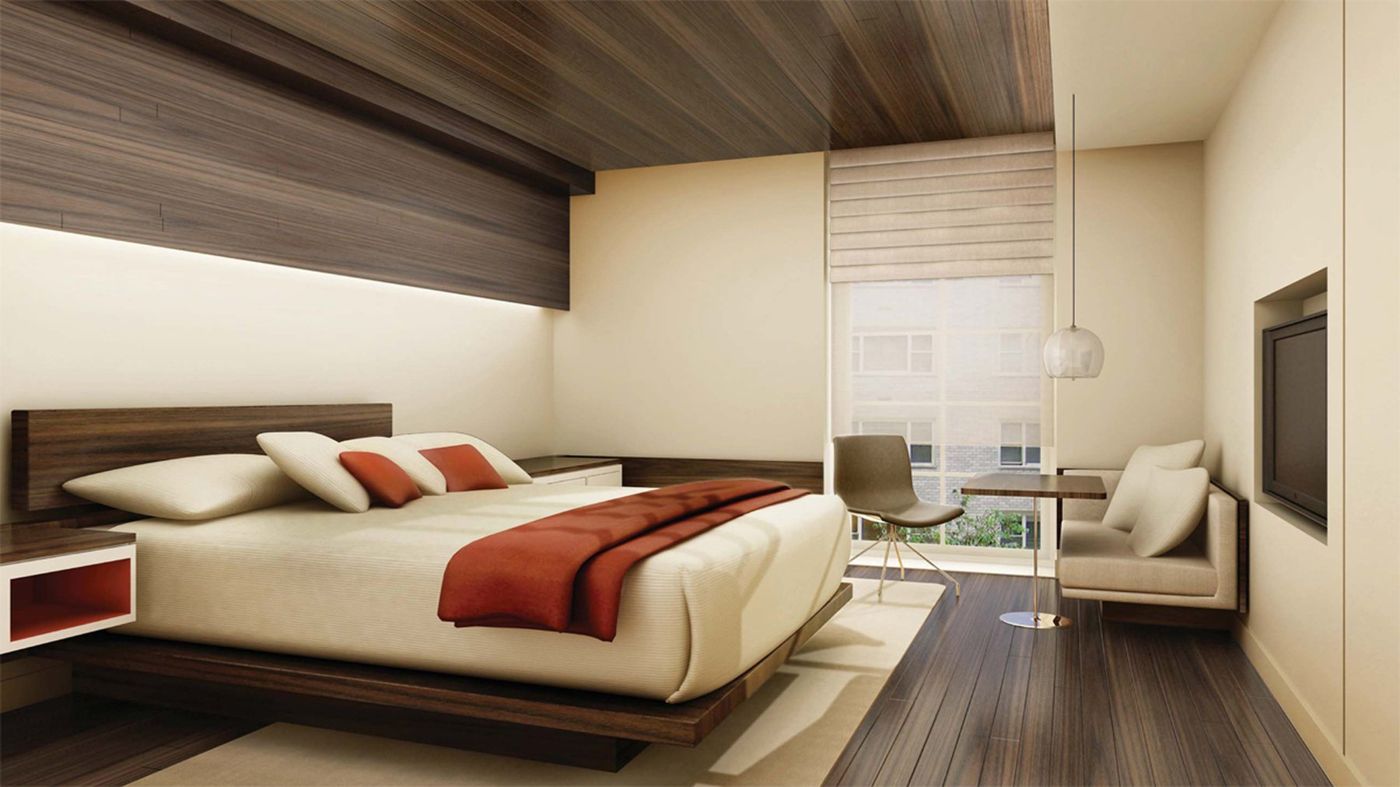 A guest room with a low timber bed, a red throw, a timber ceiling and a window seat.