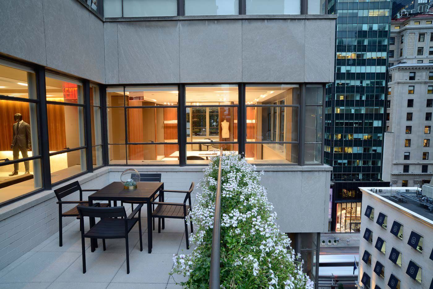 A small terrace with a table and chairs, planting, and Midtown buildings around.